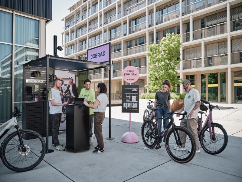 Beratungssituation am JobRad-Stand. Zentral ein Sticker-Aufsteller mit Schild "Pimp your Bike"