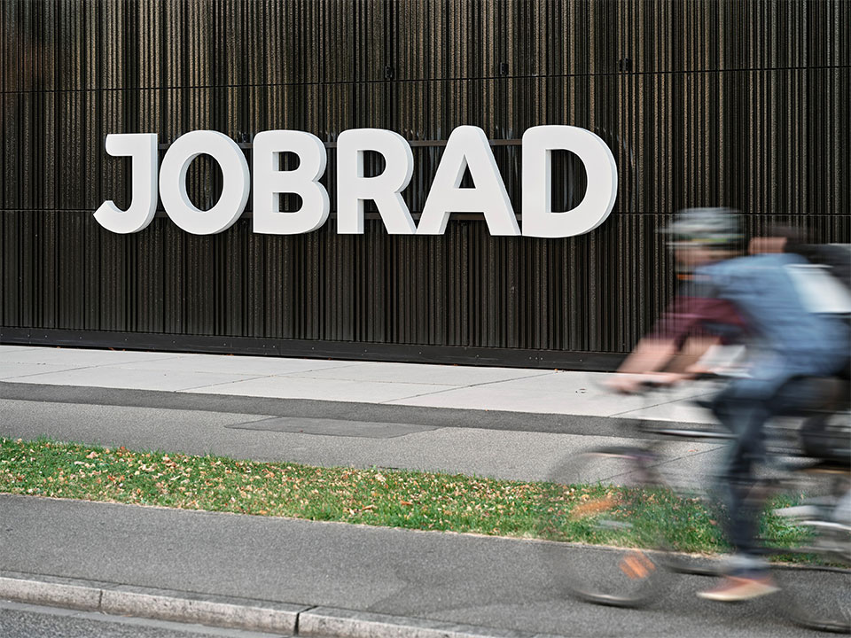JobRad-Logo am Campus in Freiburg mit Bewegungsunschärfe von Radlern die vorbeidüsen JobRad-Logo am Campus in Freiburg mit Bewegungsunschärfe von Radlern die vorbeidüsen